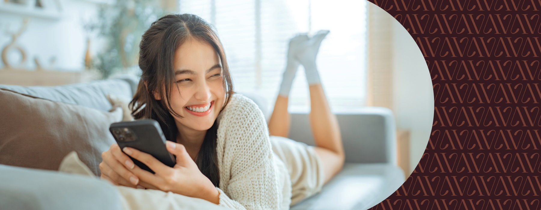 A lady holding her cell phone smiling and looking over 