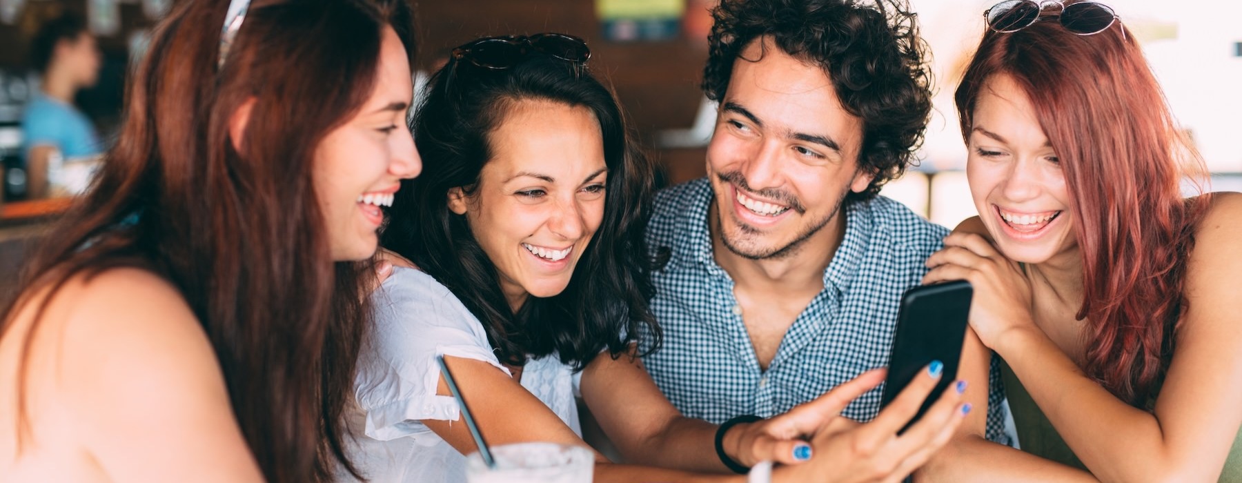 a group of people smiling and looking at a phone